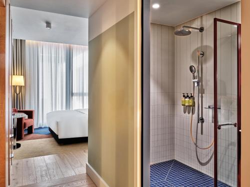 a bathroom with a shower and a bedroom at Kimpton Main Frankfurt by IHG in Frankfurt