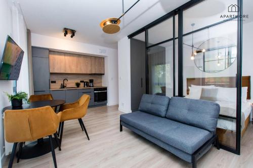 a living room with a blue couch and a bedroom at City Center - AURA by Apartmore in Gdańsk