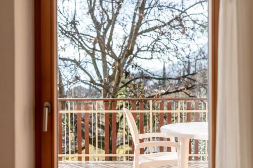 a table and a chair on a balcony with a tree at Apartments Haus Weinberg in Caldaro