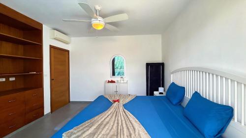 a bedroom with a blue bed and a ceiling fan at Experience the Pool View Dream at Estrella Dominicus in Bayahibe