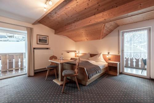 a bedroom with a bed and a desk in a room at Garni Charlotte in Selva di Val Gardena