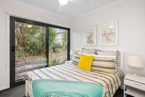 a bedroom with a bed and a large window at BYO Linen - Aireys Delight in Aireys Inlet