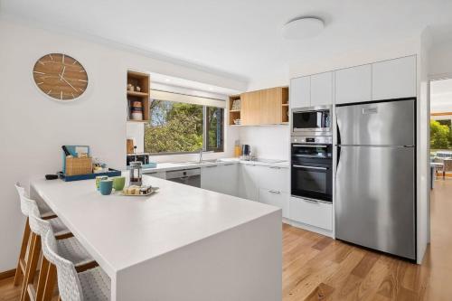 a kitchen with white cabinets and a stainless steel refrigerator at BeachHaven in Aireys Inlet