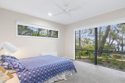 a bedroom with a bed and large windows at Alto Vista in Lorne