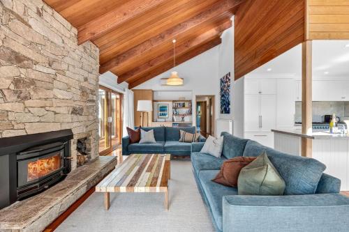 a living room with two blue couches and a fireplace at Fern House in Lorne