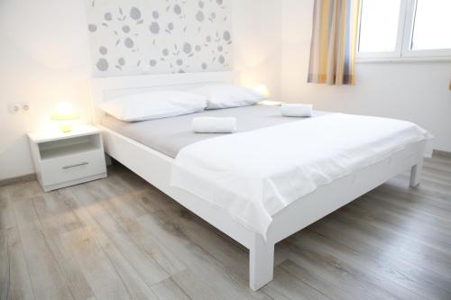 a white bed in a bedroom with a wooden floor at Apartments Gabrijel in Vodice