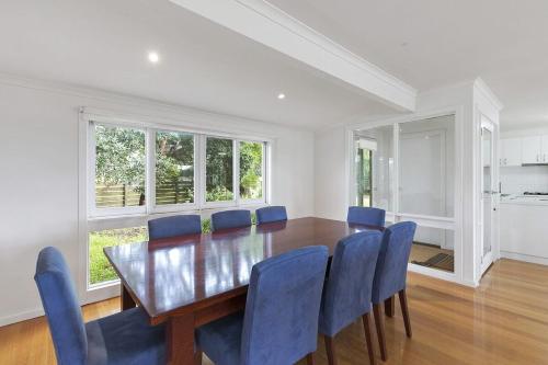 a dining room with a wooden table and blue chairs at Beach Side in Aireys Inlet