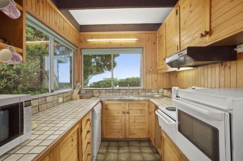 a kitchen with wooden cabinets and a large window at Aqua Blue in Apollo Bay