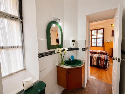 a bathroom with a green sink and a mirror at Hostal Riviera Sucre in Otavalo