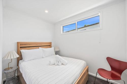 a bedroom with a bed with a red chair and a window at AquaLuna Beach House in Aireys Inlet