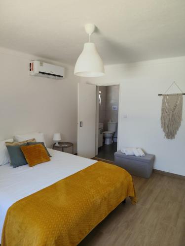 a bedroom with a large bed with a yellow blanket at Monte do Ti'Mota in São Lourenço de Mamporcão