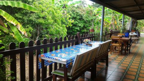 a table and chairs on a patio with a fence at Baan Benjathip in Amphawa
