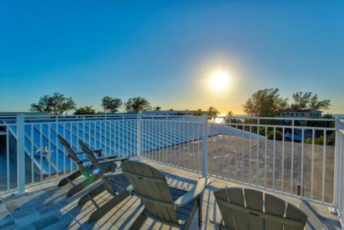 two chairs sitting on a deck with the beach at Family Tides in Holmes Beach
