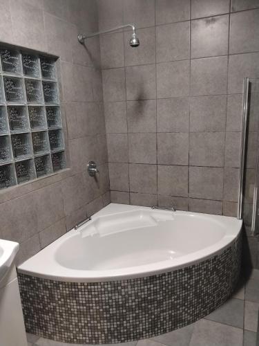 a bath tub in a bathroom with a shower at Garden Route Retreat in George