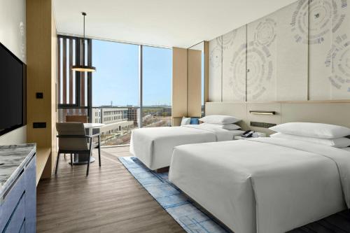 a hotel room with two beds and a desk and a television at Beijing Marriott Hotel Huairou in Huairou