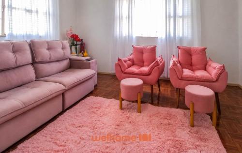 a living room with pink furniture and pink chairs at Cobertura com Vista e Conforto no RS in Santo Ângelo