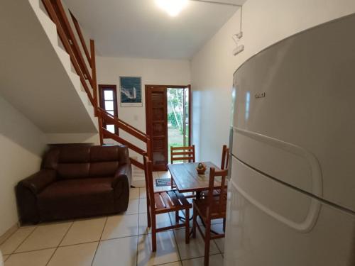 a living room with a couch a table and a refrigerator at Residencial Sol de Ibiraquera in Barra de Ibiraquera