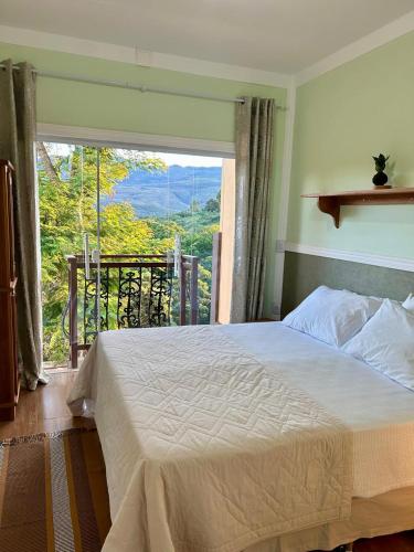 a bedroom with a bed and a large window at Pousada Canto do Luar in Conceição do Mato Dentro
