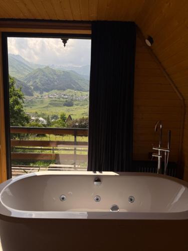 a bath tub in front of a window with a view at RestArt Cottages in Kazbegi in Kazbegi