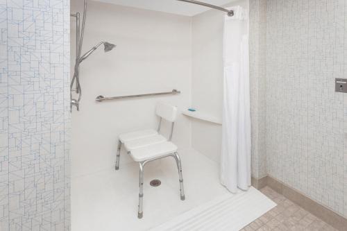a white chair in a bathroom with a shower at Holiday Inn Express Hotel & Suites Providence-Woonsocket by IHG in Woonsocket