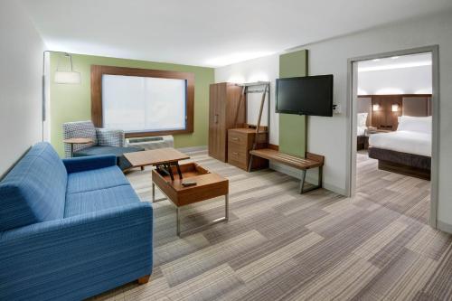 a hotel room with a couch and a bed and a television at Holiday Inn Express Woodbridge by IHG in Avenel