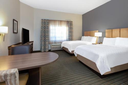 a hotel room with two beds and a desk at Candlewood Suites-West Springfield by IHG in West Springfield
