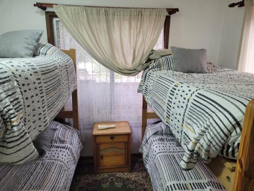 a bedroom with two beds and a table and a window at Hostal 7 norte Sporting viña del mar in Viña del Mar
