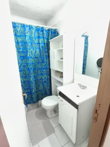 a bathroom with a white toilet and a blue shower curtain at Hostal 7 norte Sporting viña del mar in Viña del Mar