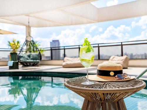 a hat and a drink on a table next to a pool at Grand Mercure SP Itaim Bibi in São Paulo