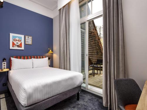 a bedroom with a bed and a large window at ibis Styles London Gloucester Road in London