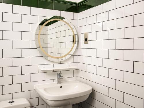 a white tiled bathroom with a sink and a mirror at ibis Styles London Gloucester Road in London