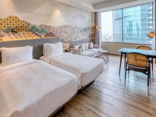 a hotel room with two beds and a table at Mercure Jakarta Gatot Subroto in Jakarta