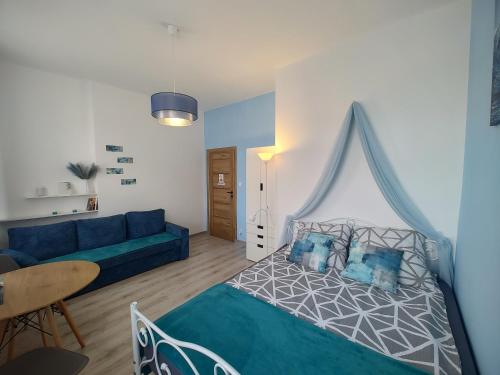 a bedroom with a bed and a blue couch at Magnolia Home Rooms in Toruń