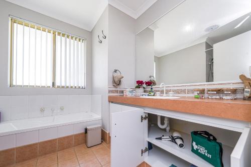 a white bathroom with a tub and a sink at Waves And Moore - Beautifully presented home in Guilderton