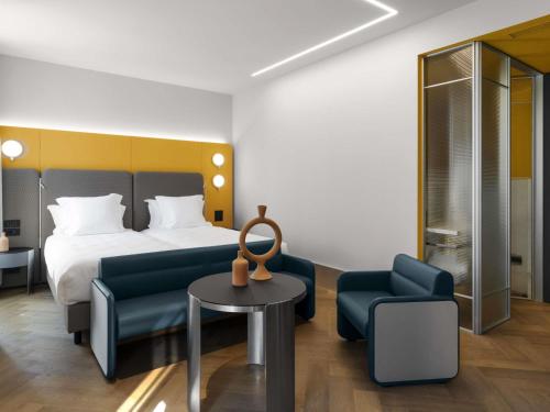 a hotel room with a bed and a table and chairs at Palazzo Tirso MGallery Cagliari in Cagliari