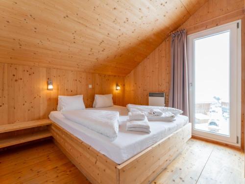 a large bed in a wooden room with a window at Das Edelweiss in Hohentauern