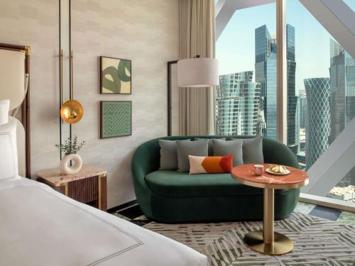 a bedroom with a green couch and a large window at Swissôtel Corniche Park Towers Doha in Doha