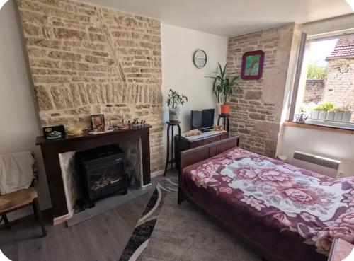 a bedroom with a brick wall and a bed and a fireplace at L Ecrin de Mussy in Mussy-sur-Seine
