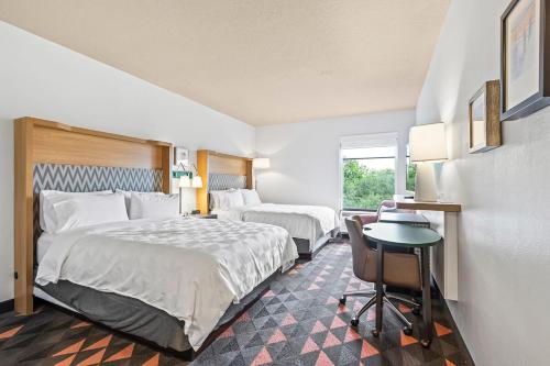 a hotel room with two beds and a desk at Holiday Inn - St. Petersburg West by IHG in St. Petersburg