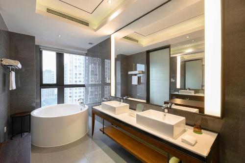 a bathroom with two sinks and a tub and a large mirror at Holiday Inn Kunshan by IHG in Kunshan