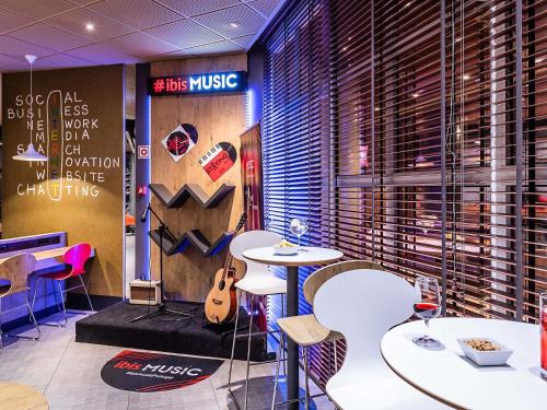 a restaurant with white tables and chairs and a guitar at Hotel ibis Porto Gaia in Vila Nova de Gaia