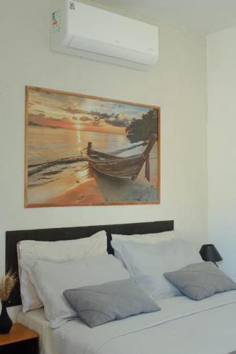 a painting of a boat hanging above a bed at Wind Village Icaraizinho in Icaraí
