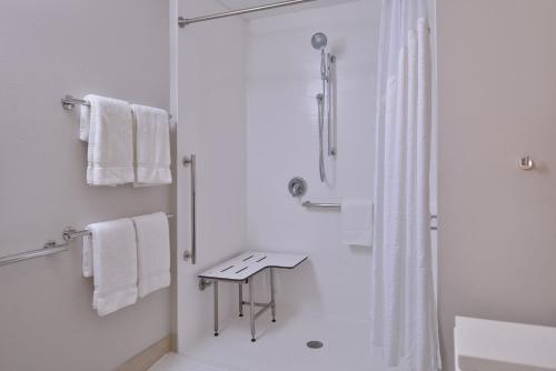 a white bathroom with a shower and a sink at Holiday Inn Express & Suites - Marshalltown by IHG in Marshalltown