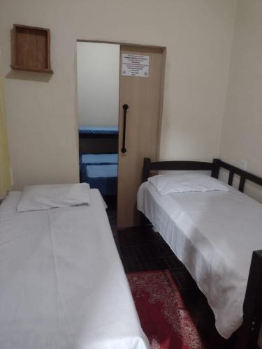 two beds in a room with a door to a room with a door at Casa lai in Rio de Janeiro