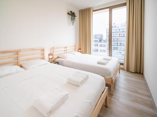 two beds in a room with a large window at Spacious City Retreat with Balcony in Antwerp