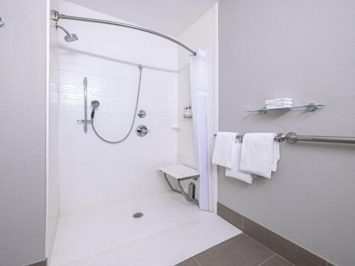 a white bathroom with a shower with white towels at Garner Hotel Longview South by IHG in Longview