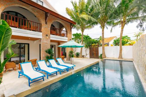 a pool with chairs and an umbrella next to a house at Salt Villa 5BR Beachfront by HUA in An Bàn (2)