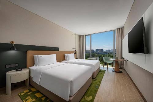 a hotel room with two beds and a flat screen tv at Holiday Inn Beihai Silver Beach in Beihai