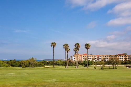 a park with palm trees and a building in the background at Palacio de Sancti Petri, a Gran Meliá Hotel - The Leading Hotels of the World in Chiclana de la Frontera