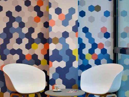 two chairs and a table in a room with geometric wallpaper at ibis Styles Montelimar Centre in Montélimar